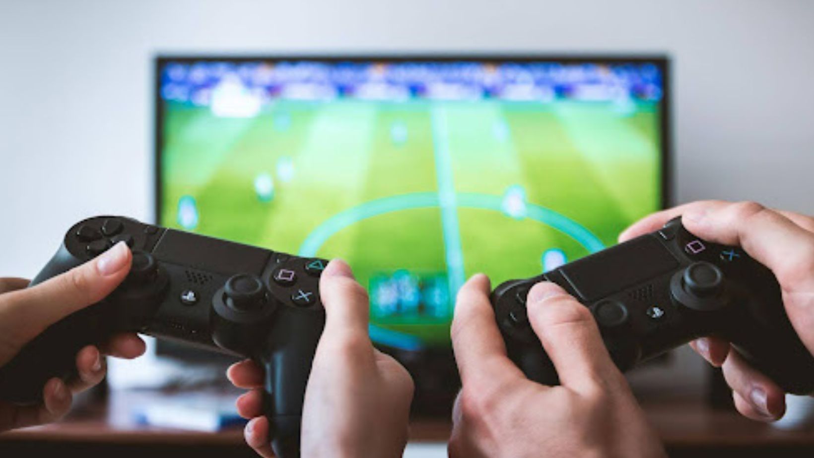 Two hands holding controllers while playing a video game on a TV.
