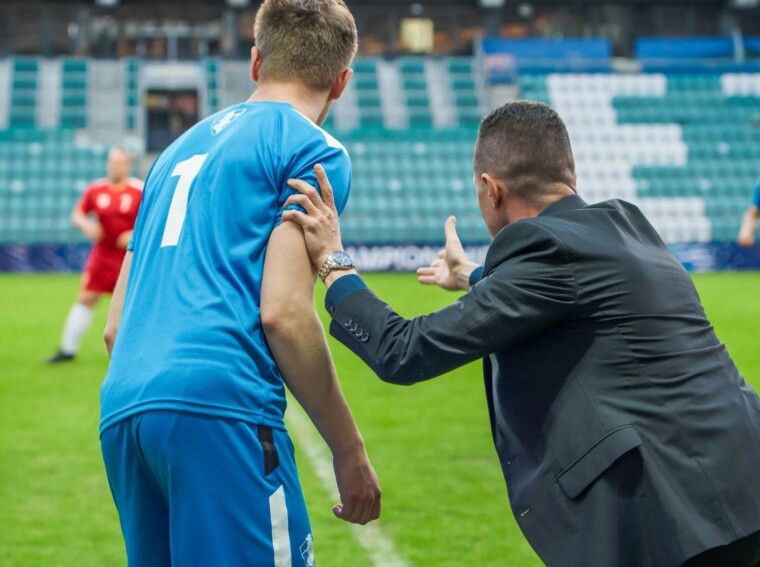 Football coach giving tactical instructions to a player during a match